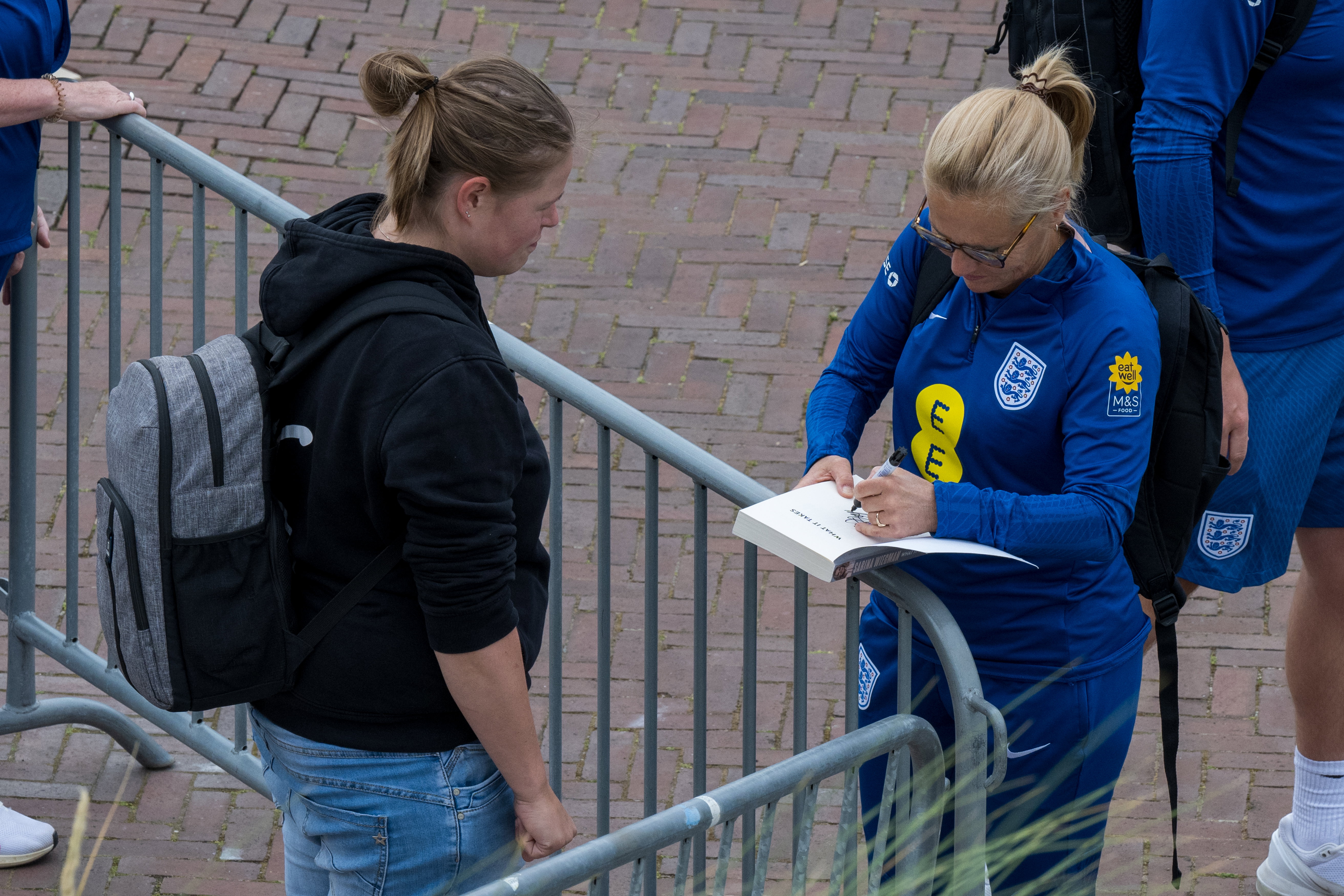 Sarina Wiegman signeert haar boek voor een fan bij de open training