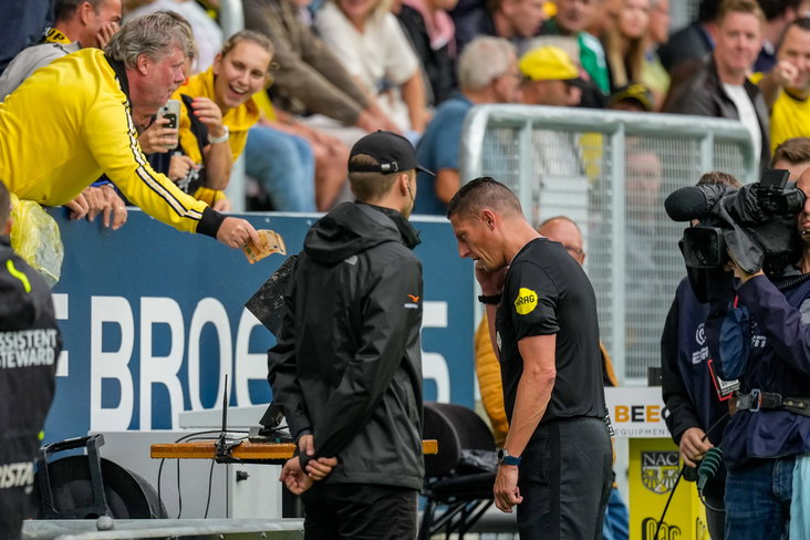Jeroen Manschot krijgt geld aangeboden van een NAC-fan tijdens een VAR-check