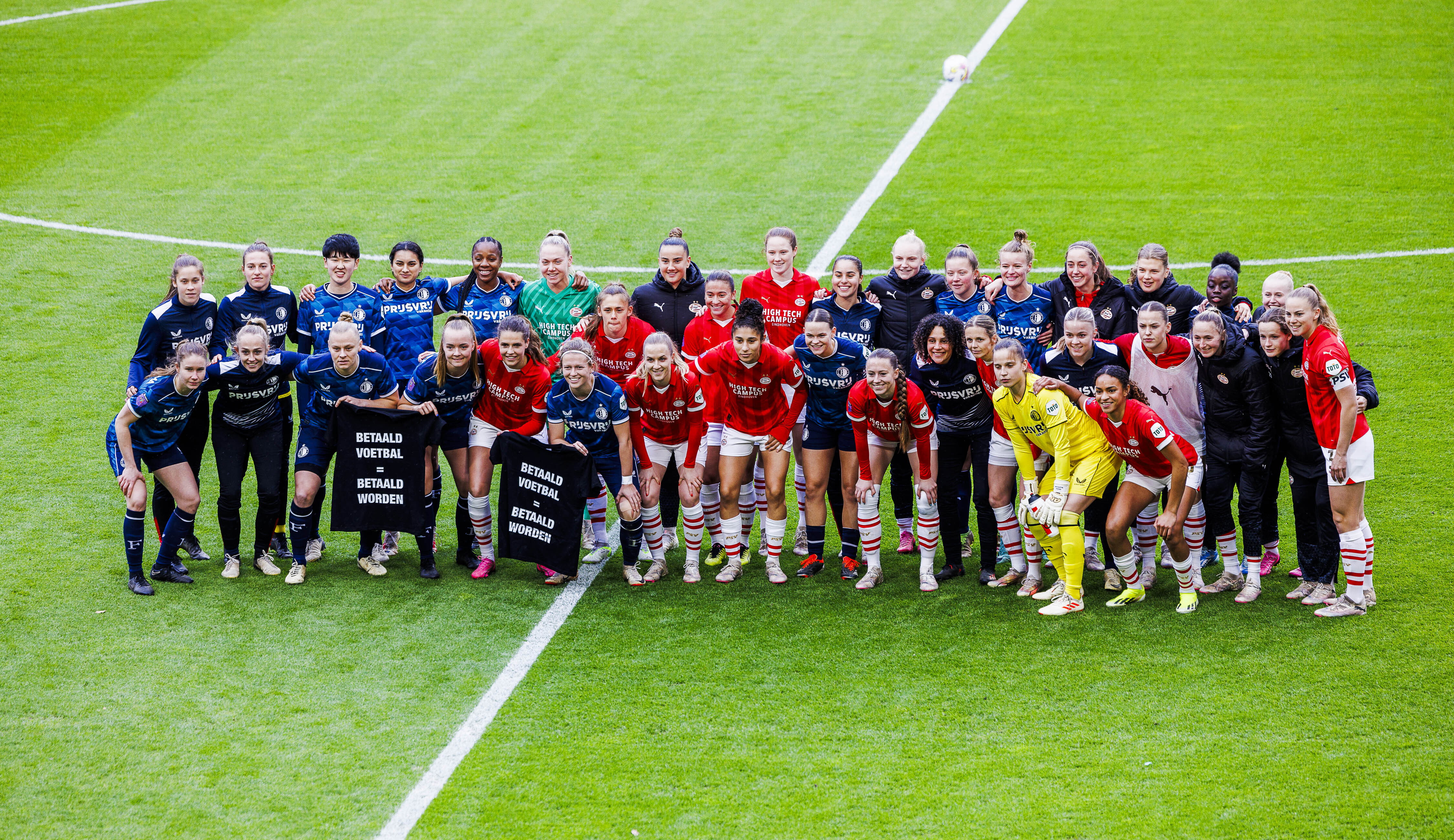 De speelsters van PSV en Feyenoord tonen een shirt met 'betaald voetbal = betaald worden'