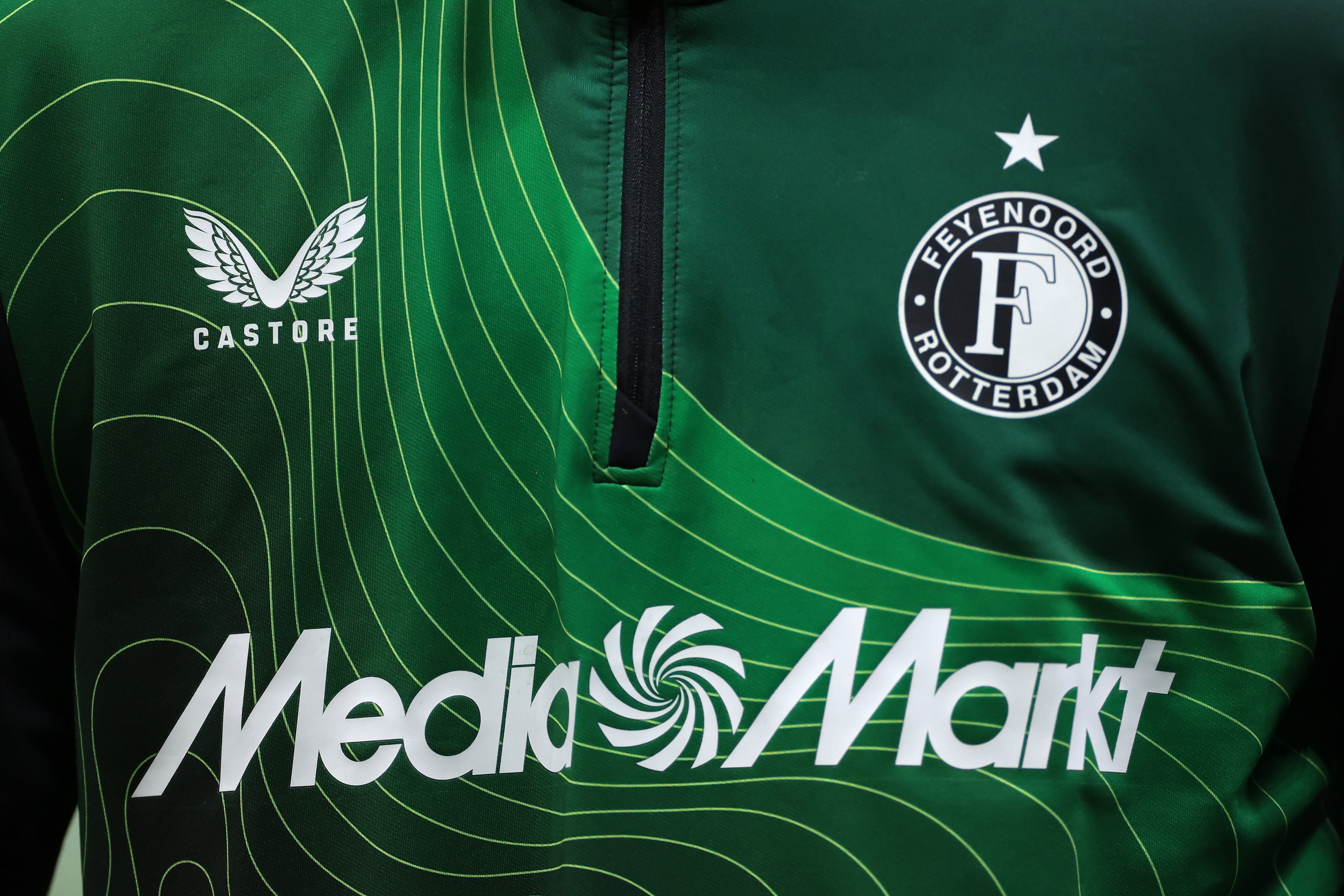De logo's van Feyenoord, Castore en MediaMarkt op een jack van Feyenoord