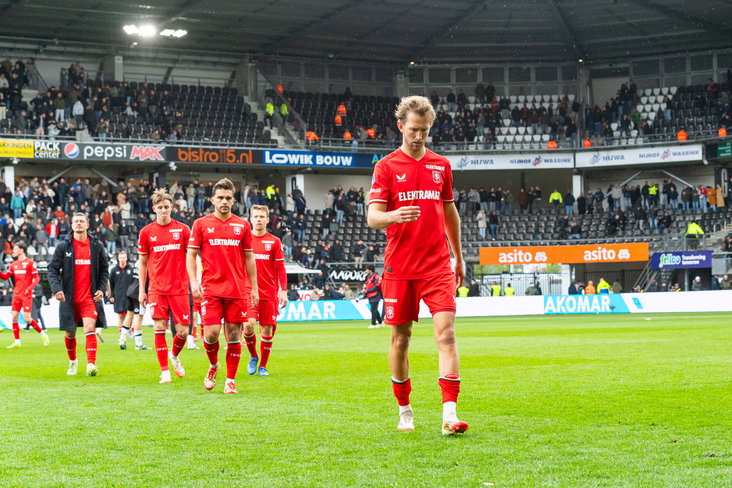 De spelers van FC Twente druipen af na de derbynederlaag