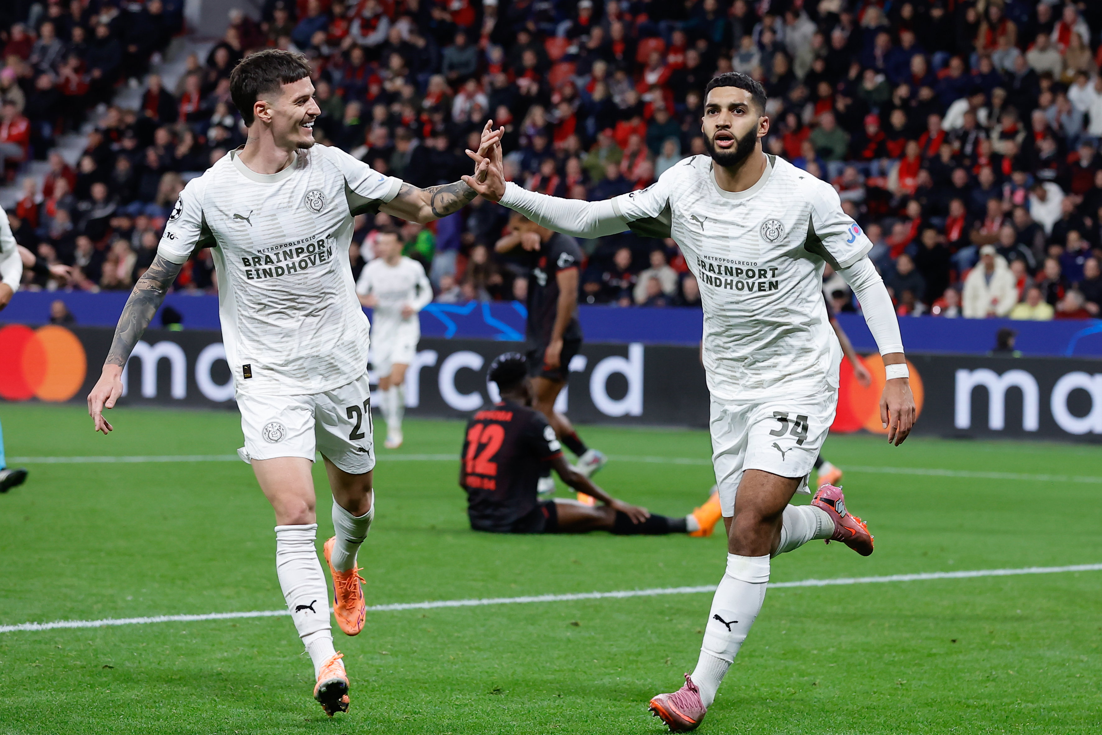 Dennis Man en Ismael Saibari vieren de goal tegen Bayer Leverkusen