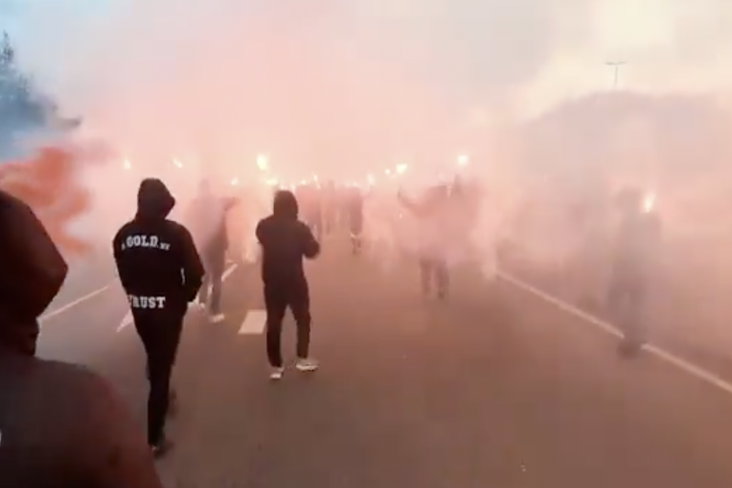 Enthousiaste Ajax-supporters zwaaien de spelersbus uit