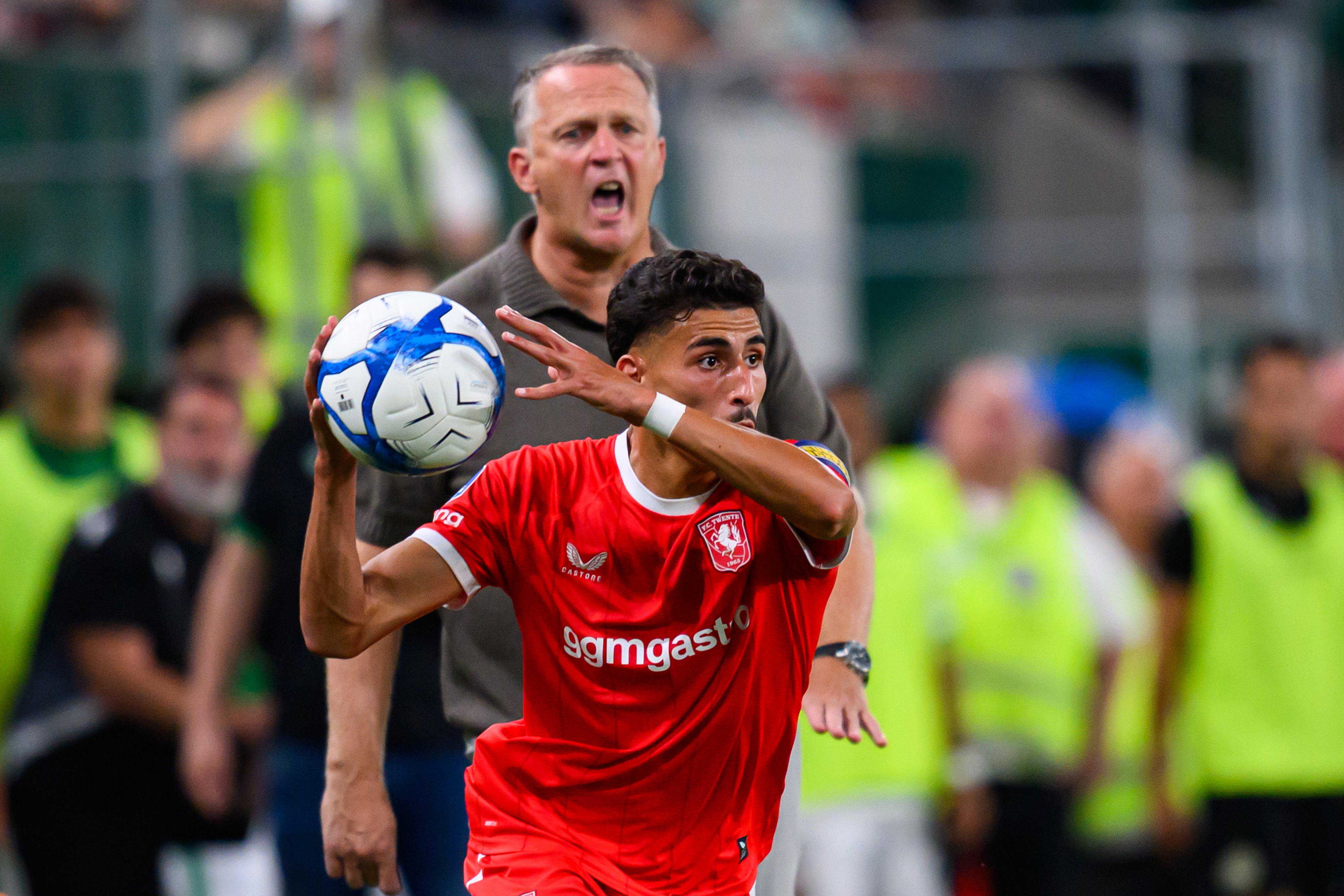 Younes Taha gooit een bal in met John van den Brom op de achtergrond