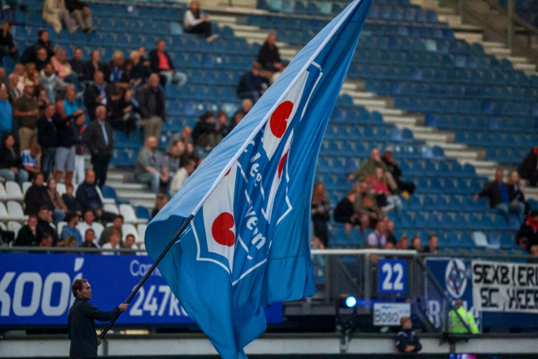 Een vrijwilliger zwaait de vlag voorafgaand aan een thuisduel