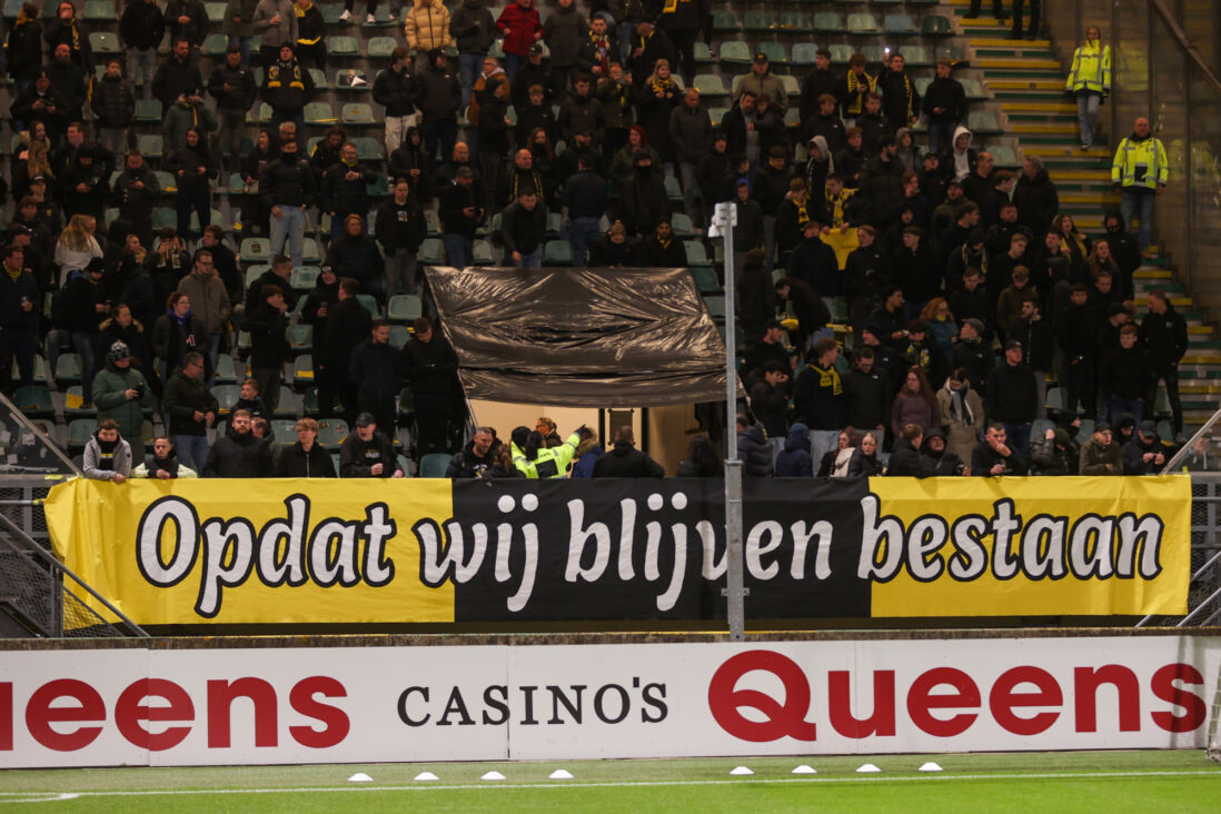 Een spandoek bij Vitesse met de tekst: 'Opdat wij blijven bestaan'