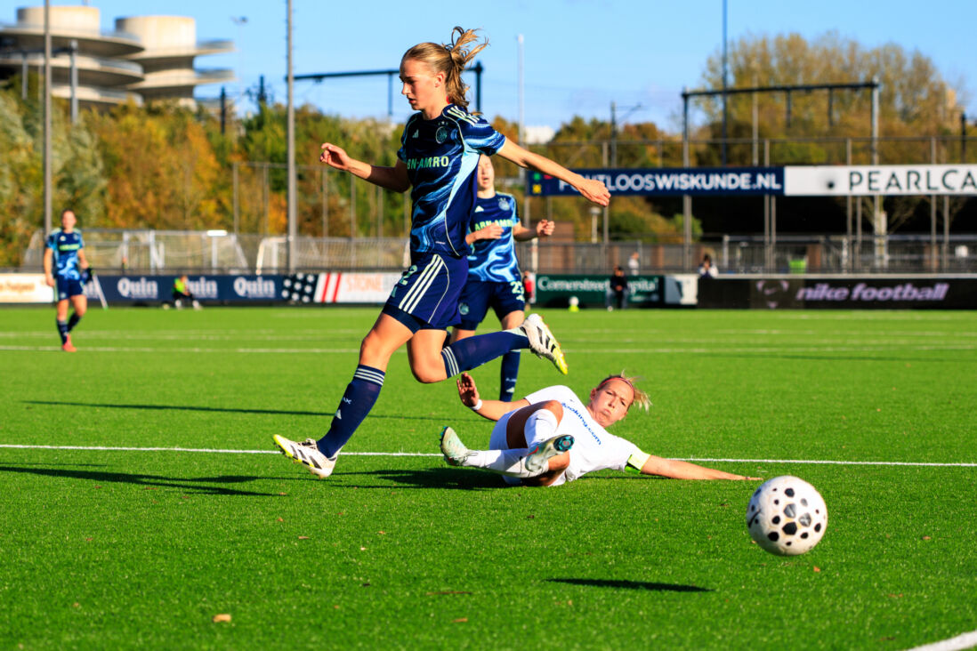 Puck Donker (HERA United) zet een sliding in bij Jade van Hensbergen (Ajax)