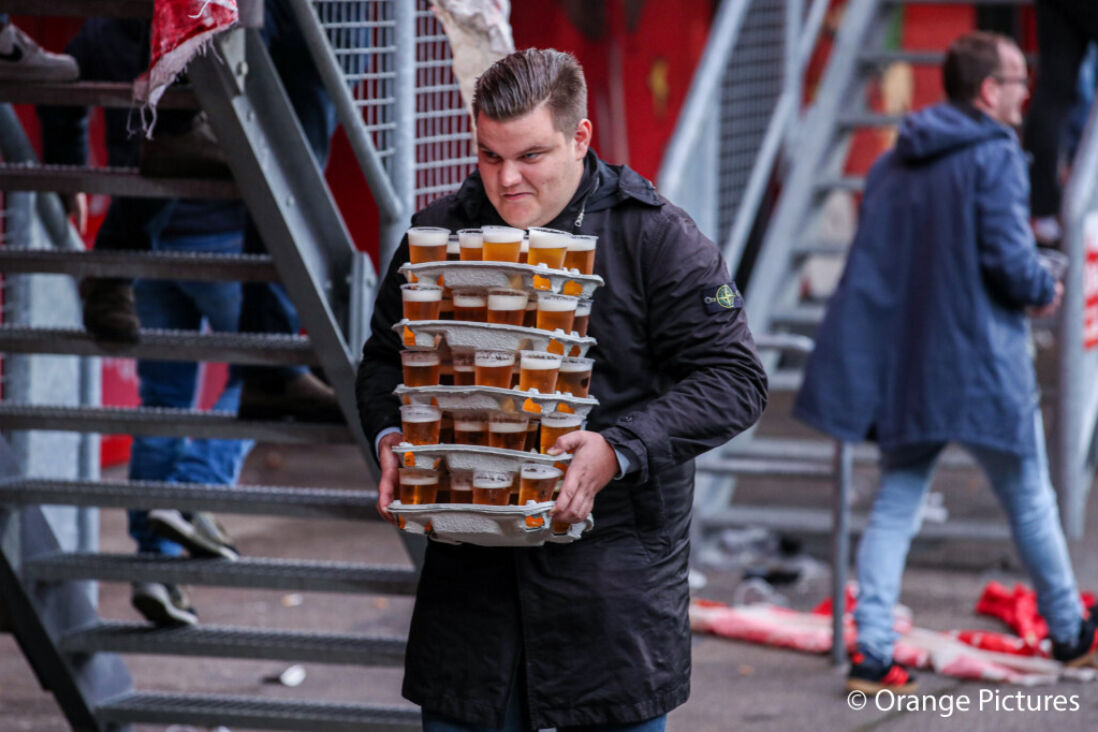 Een supporter van FC Twente sleept met een hele lading bier