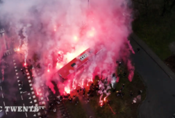 De spelersbus van FC Twente vertrekt door een haag van fakkels naar Tilburg