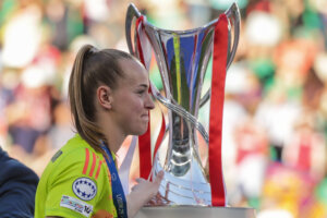 Daphne van Domselaar loopt langs de UEFA Women's Champions League-trofee