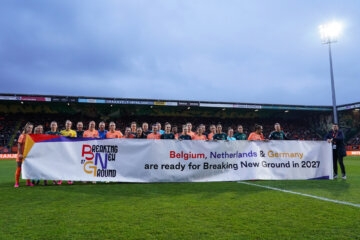 De speelsters van de OranjeLeeuwinnen en Duitsland met een banner voor het bid voor het WK 2027