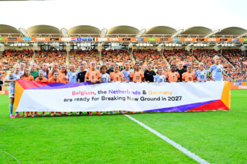 De speelsters van de OranjeLeeuwinnen en België met een banner voor het bid voor het WK 2027