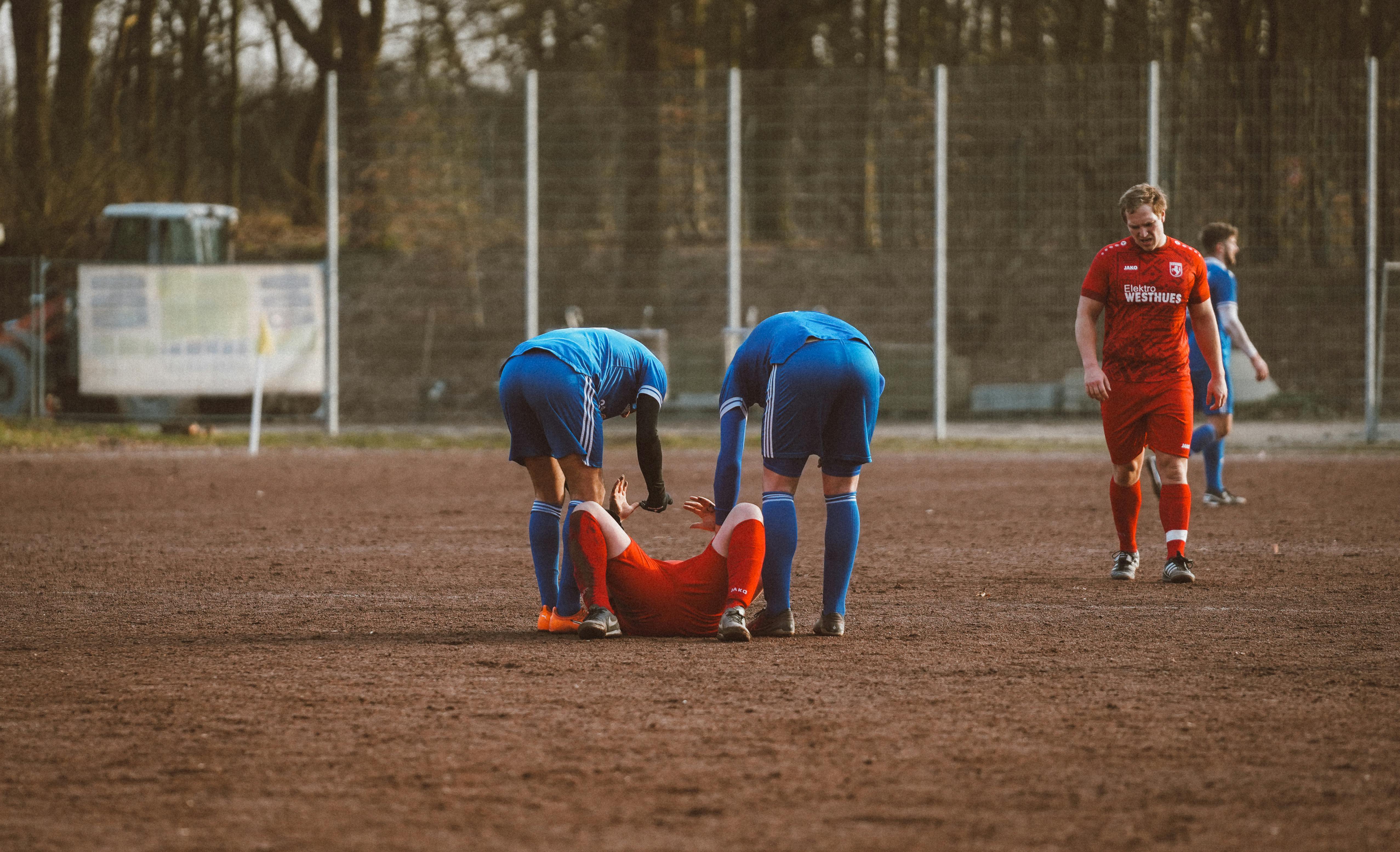 Voetballers helpen een geblesseerde speler