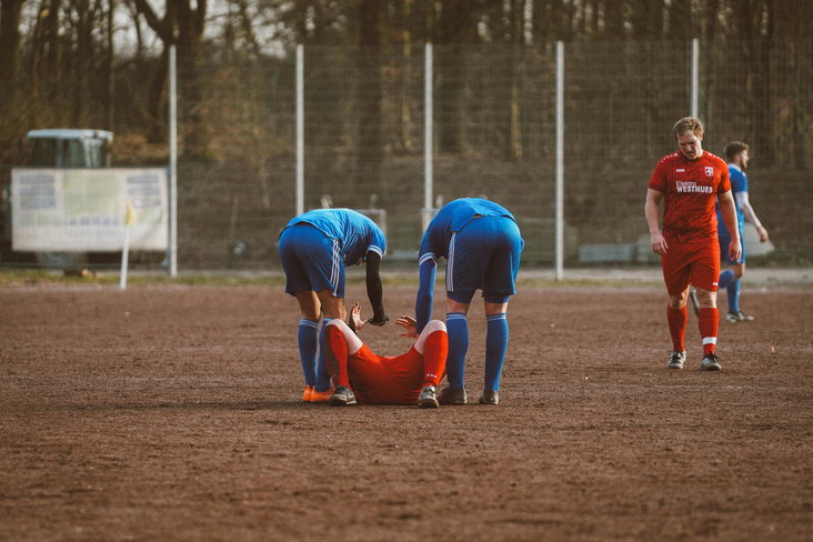 Voetballers helpen een geblesseerde speler